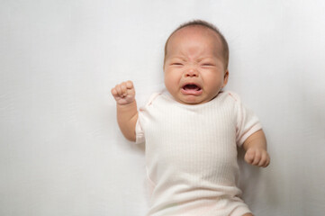 Asian baby infant girl crying and screaming lying on bed