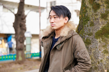 Fototapeta premium 公園の木の近くで待つアジア人男性