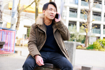 公園で電話をするハンサムな日本人男性