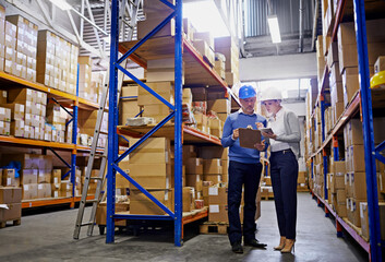 We know where every order is in this warehouse. Shot of a man and woman inspecting inventory in a...