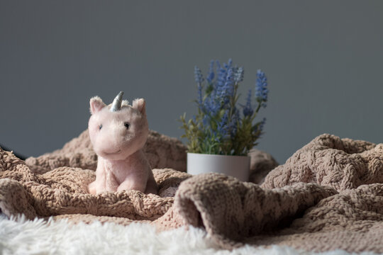 Tiny stuffed unicorn on a bed with lavender plant