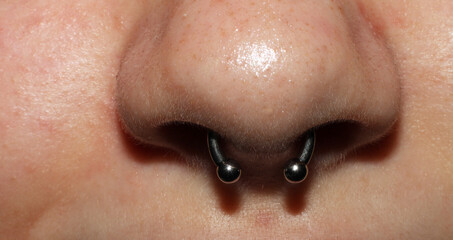 Girl's nose piercing.
Septum piercing. Macro.
Titanium piercing jewelry with balls. - obrazy, fototapety, plakaty