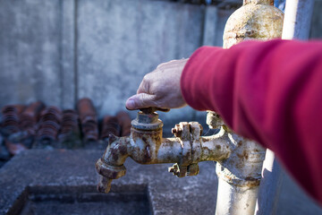 A male hand on an old fashioned rusted water pump opening the pipe into abandoned place. Climate...