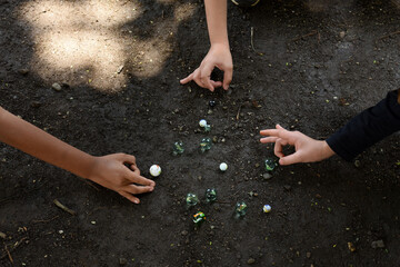 Children playing with marbles in the yard of the house. Traditional game, shared section of group game, inclusion  and Socialization