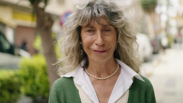 Middle age woman smiling confident holding bitcoin at street