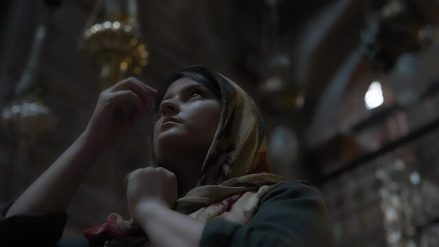 Religious woman in traditional clothes praying inside the christian orthodox church. Slow motion. 