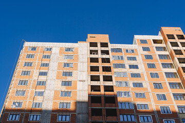 The house is made of red brick against the blue sky. Construction of the building from concrete view from the outside. Facade of the house.