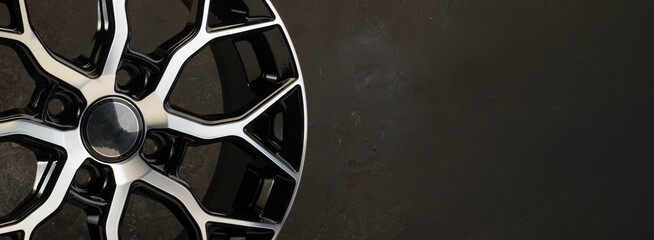 new black alloy wheels on a dark textured black background. wheel for car spare parts auto repair...