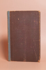The cover of an old worn book on a colored background