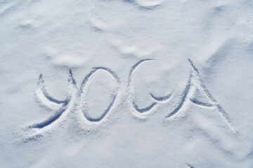 The word yoga is written in the snow. The letters of the meditation of the Vedic culture on a white background. The concept of Zen is a symbol of calm and quiet.