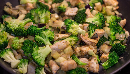 A delicious Chinese dish is fried chicken with broccoli in a wok. The process of cooking chicken with broccoli vegetables in a steel pan. Teriyaki chicken and broccoli in a cast-iron pan. 