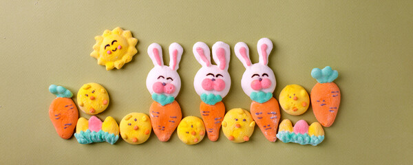 Fototapeta na wymiar Happy Easter concept. Preparation for holiday. Easter marshmallow candy chiken, rabbit, carrot, bunny on green pastel background. Simple cute, funny minimalism flat lay top view, copyspace banner