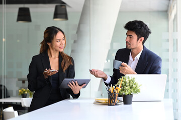 Two successful young entrepreneurs collaborating on a new project together at modern office.