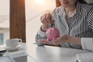 Obraz na płótnie Canvas Woman hand putting coin into piggy bank. Saving money for future, retirement fund, business investment, finance concept.