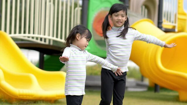Slow motion shot, Two Asian cute girl slowly play with extend the arms and smile with happy together at playground