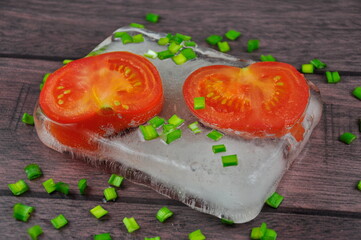 Red fresh tomatoes and green onions on a wooden table.