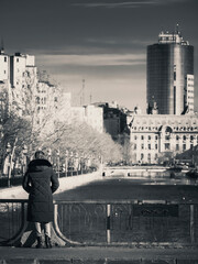 Lonely woman on Eroilor (Heroes) bridge looking at Dambovita River in Bucharest, Romania.