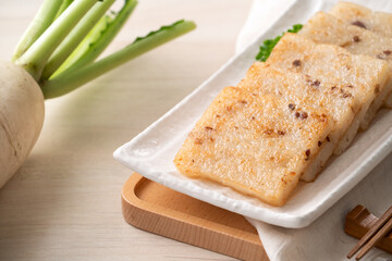 Delicious Chinese radish cake in a plate on wooden table background.