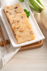 Delicious Chinese radish cake in a plate on wooden table background.