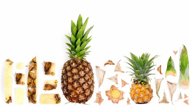 Pineapple fruit pieces, slices and leaves being moved isolated on white. Top view. Seamless looping. High quality 4k video.