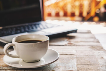 .A cup of coffee and a notebook computer on the desk