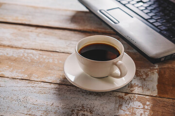 .A cup of coffee and a notebook computer on the desk