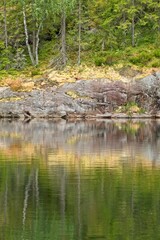 View of rocky lake shore with reflection at Nuuksio National Park, Espoo, Finland.