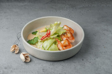 green salad with fried shrimps on gray background