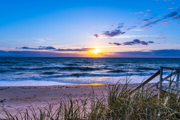 Sunrise on the beach in the Atlantic Ocean, Melbourne Beach, Florida. View from the veranda of a private house in the early morning. The sun shines through the clouds and is reflected in the restless 