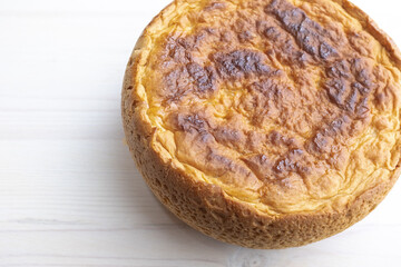 Freshly baked bread on white table, top view. A round bread lies on the right side of surface for publication, poster, calendar, post, wallpaper, card, cover, website, space for your design or text