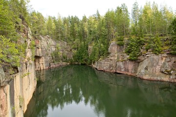 Old rock quarry filled with water in summer at Vehmaa, Finland.