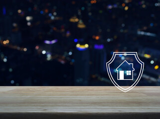 Fototapeta na wymiar House with shield flat icon on wooden table over blur colorful night light modern city tower and skyscraper, Business home insurance and security concept