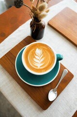 Top view of Hot cappuccino coffee in a blue mug placed on a wooden table.