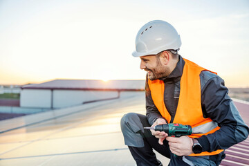 Obraz premium A worker setting solar panels on roof at sunset.