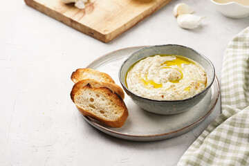 Traditional dish of arabic cuisine baba ganoush made of roasted eggplant, tahin, cilantro, garlic, olive oil, lemon juice with toasted baguette croutons on grey background