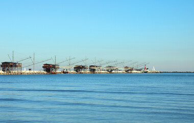 Obraz premium fishing huts on the dike and large nets for catching fish and crustaceans in the Adriatic sea in Italy