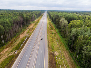 Aerial top view of a country road through a fir forest in summer