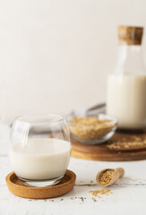 Oat milk in glass and bottle with whole grain oats