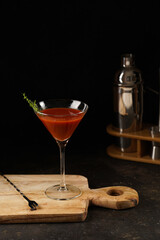 Red non-alcoholic tomato cocktail on wooden board on black background and bar equipment