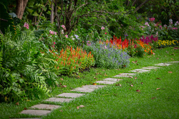 Background image of a garden path with colorful flowers planted beside it.