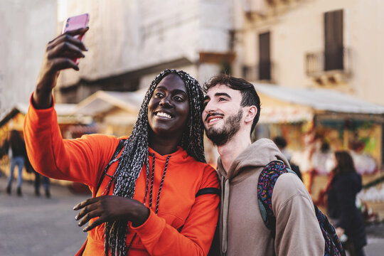 interracial couple of young people taking a selfie to the city market - tourists shooting moments together