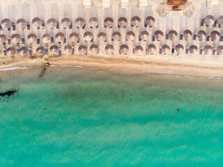 Aerial top view of sandy beach and turquoise sea, with umbrellas and sun loungers in Beautiful sunny summer day