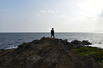 Fototapeta na wymiar 岩の海の先端に立つ男性