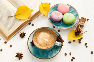 Coffee cup, macaroons and book on white background