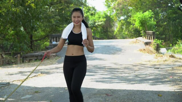 fitness asian woman  wearing sportswear and towel Walk and lead the dog together on road  in park outdoors . friend with pet in morning healthy lifestyle.
