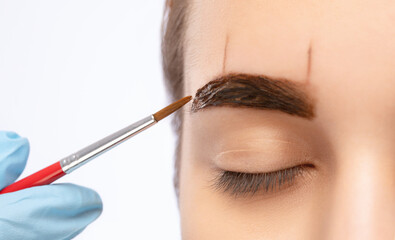 Make-up artist makes markings for eyebrow and paints eyebrows. Professional makeup and facial care.