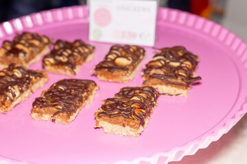 Vegan dessert coated with chocolate on top on a pink plate.