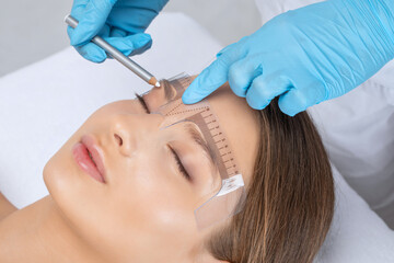 Make-up artist makes markings with white pencil for eyebrow and paints eyebrows. Professional...