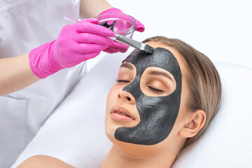 Beautician does Carbon peeling procedure to a beautiful woman. Hardware cosmetology treatment in the beauty salon.