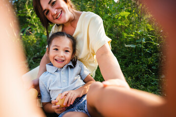 European mother and her Asian daughter in the apple garden in summer